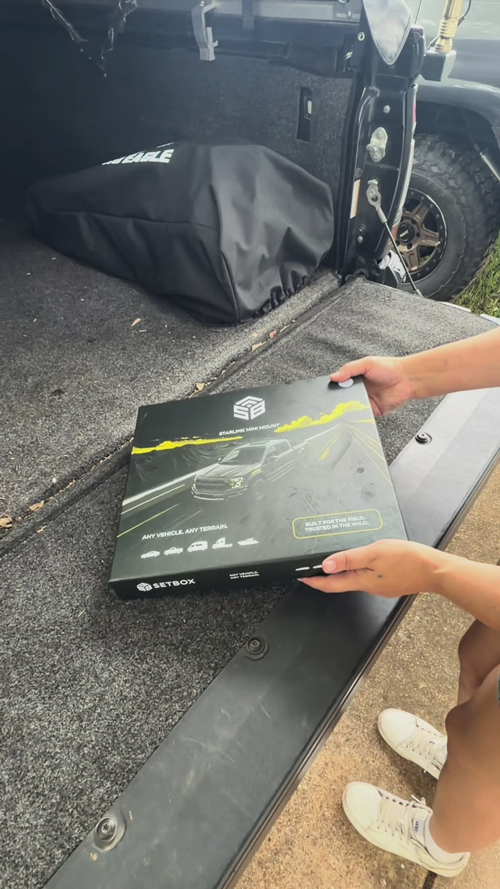 Hands lifting the SETBOX retail box off the open tailgate of a pickup
